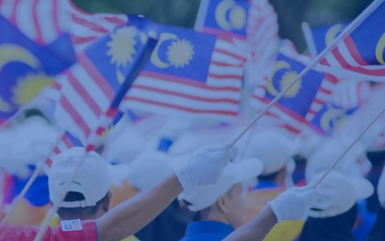 Malaysian flags held up in a crowd.
